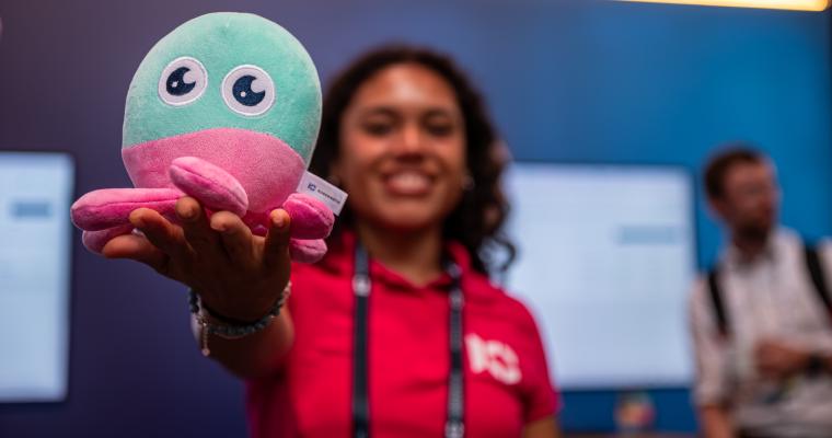 Kubermatic team member holding the company's pink and teal octopus mascot plush toy at the ContainerDays Hamburg 2026 booth